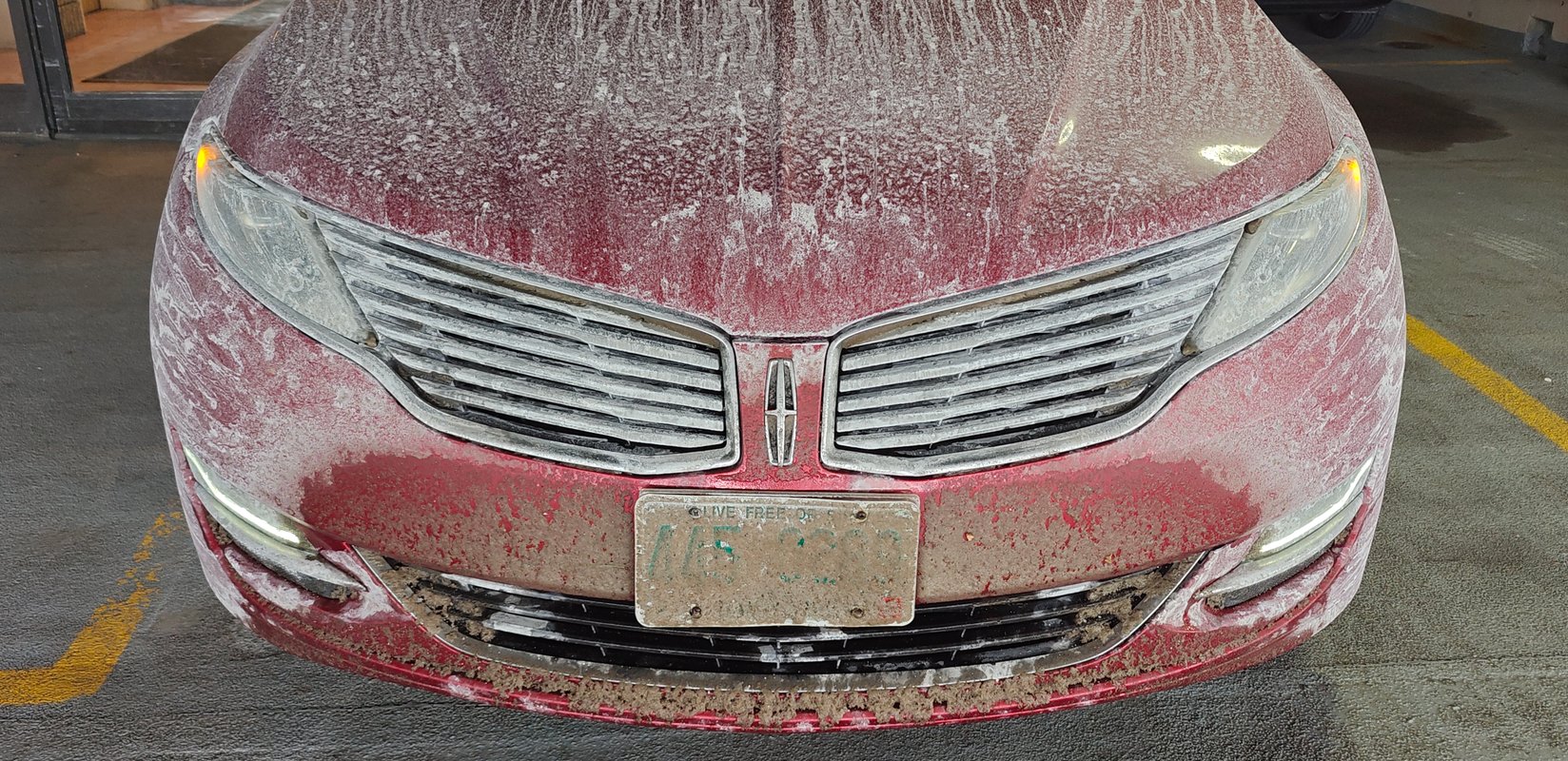 Picture of car parked in a garage, covered in salt and snow from a long drive down from the North